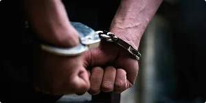 A close-up of a person's hands secured in handcuffs, resting on a surface.