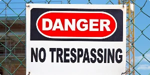 1. A danger sign on a chain-link fence, featuring a red background with white text stating "Danger" and "No Trespassing" below.
