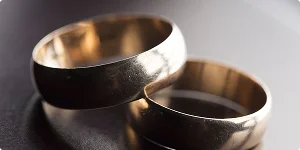 Two gold wedding rings placed on a table, symbolizing a marriage now facing the sadness of divorce.