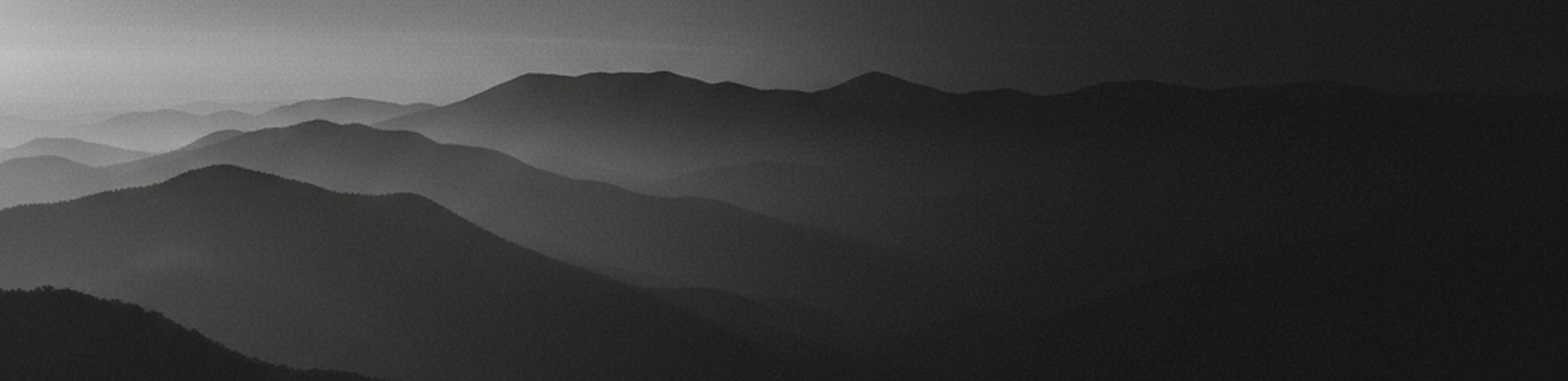 Layered mountain ridges fading into the distance in black and white.