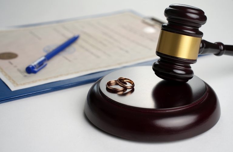 Judge gavel with wedding rings and divorce decree