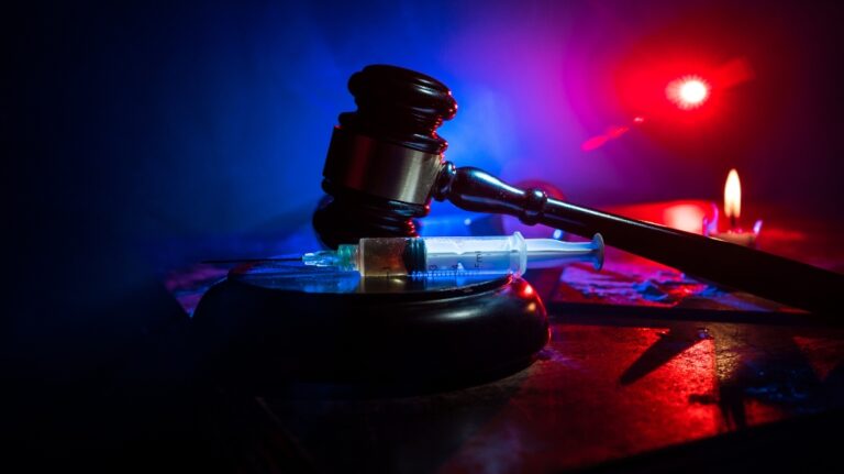 Drug syringe and narcotic attributes on wooden table