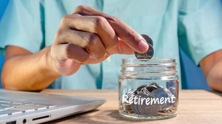 man is putting coins into a glass jar to prepare for retirement