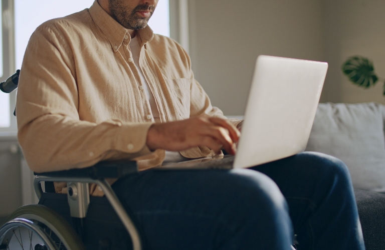 man with disability working on laptop in wheelchair