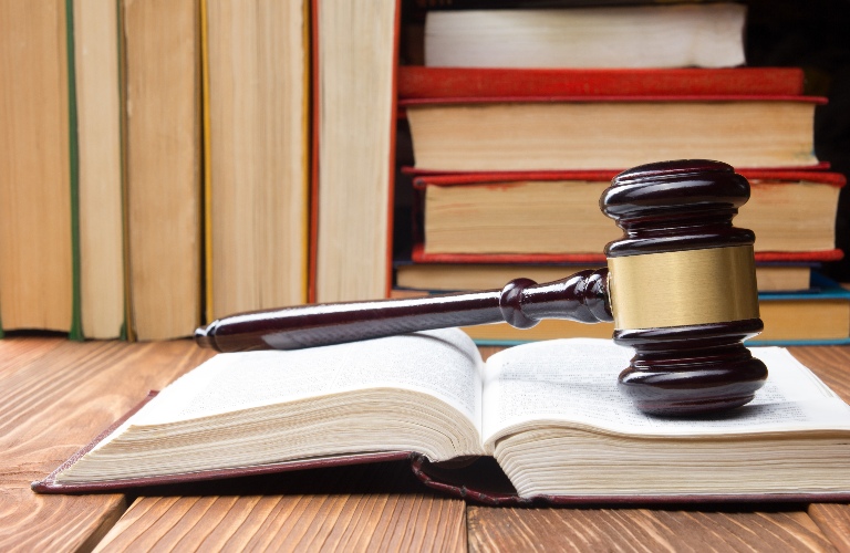 Open law book with a wooden judges gavel on table