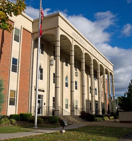 A sunny courthouse with tall columns, an American flag, and blue sky.