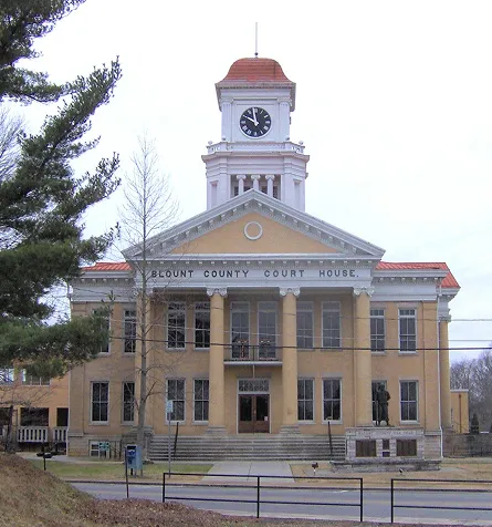Friendly old courthouse with tall columns and a big clock tower on top.