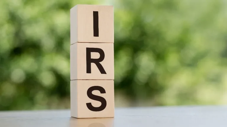 Three wooden blocks stacked with letters I, R, and S in black on a blurred green background.