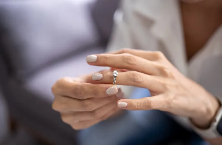 Close-up of hands holding a sparkly engagement ring with a big diamond.