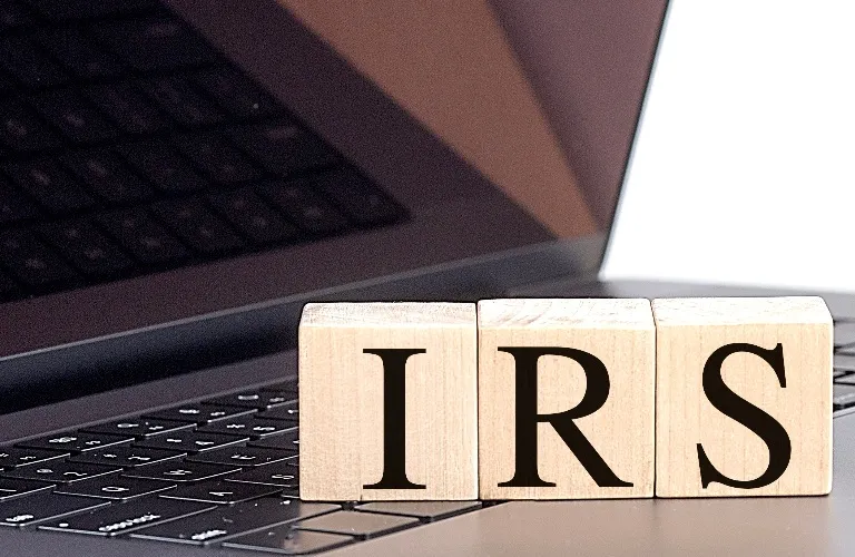 Wooden blocks with letters "IRS" sitting on a laptop keyboard, soft lighting.