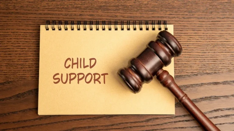 A wooden gavel resting on a notebook with "Child Support" written on it.