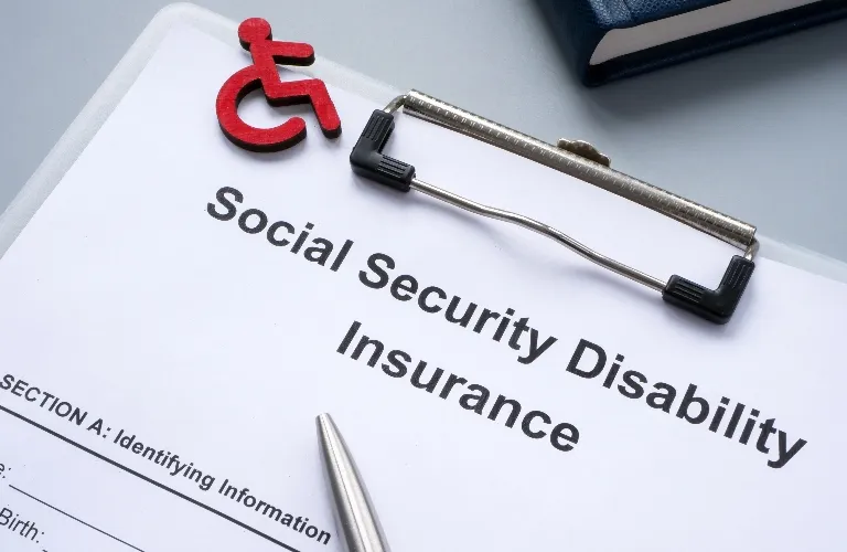 A clipboard with a Social Security Disability Insurance form and a red wheelchair symbol on top.