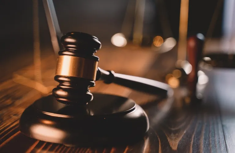 Close-up of a wooden judge’s gavel resting on a dark wooden table with warm lighting.