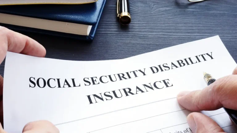 Hands holding a Social Security Disability Insurance form with a pen nearby.