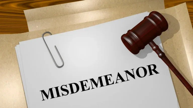 Stack of papers with "MISDEMEANOR" written on top and a wooden judge's gavel nearby.