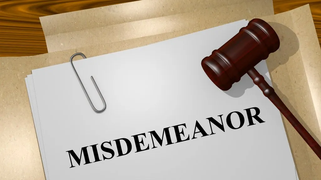 Stack of papers with "MISDEMEANOR" written on top and a wooden judge's gavel nearby.