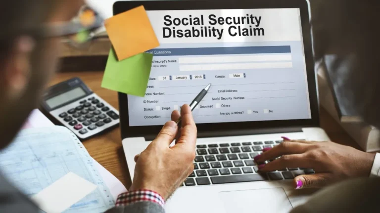 Two people filling out a Social Security Disability Claim form on a laptop.