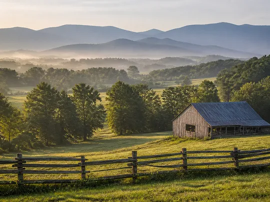 A peaceful countryside scene with a wooden barn, green trees, and misty mountains.