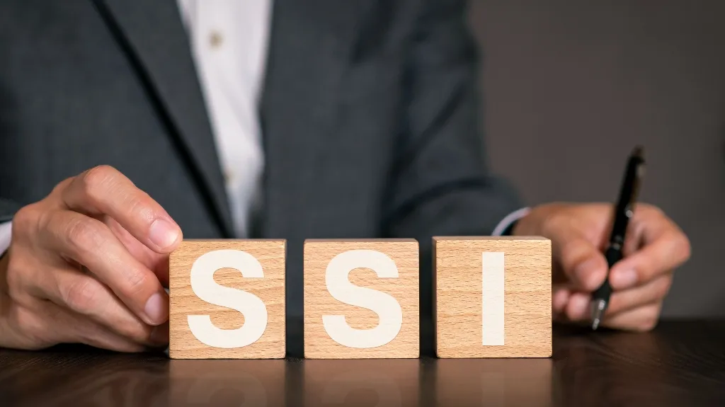 Person in suit arranging wooden blocks with letters S, S, and I on a table.
